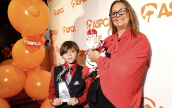 Donna con gatto in costume e ragazzo con trofeo a un evento ASPCA.