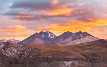 Cime argentine innevate al tramonto, nuvole luminose, terra dei dinoidi.