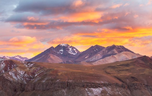 Cime argentine innevate al tramonto, nuvole luminose, terra dei dinoidi.